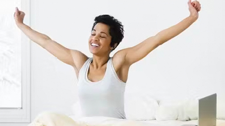 Happy woman stretching in bed